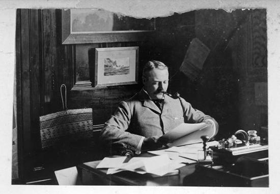 man at his desk smoking a pipe