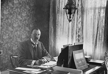 Lord Ranfurly writing at his desk - click for more
            detail