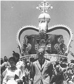 Queen and Prince in front of large crown